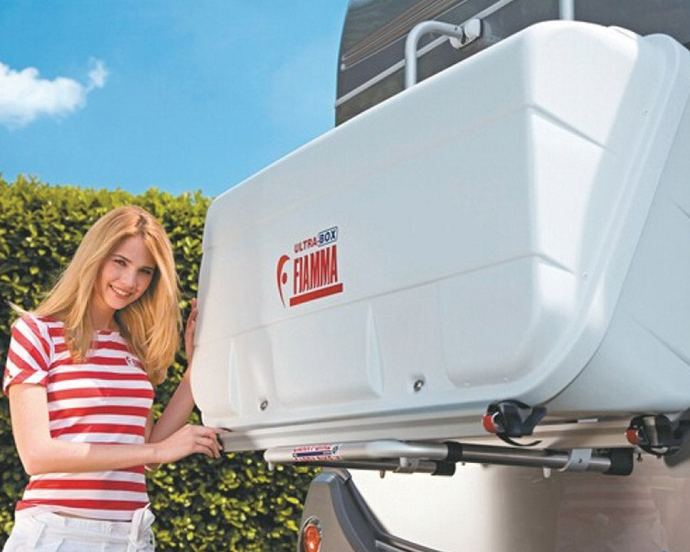 ultrabox hvit montert på en bobil, og en dame med rødstripete genser er i ferd med å åpne boksen