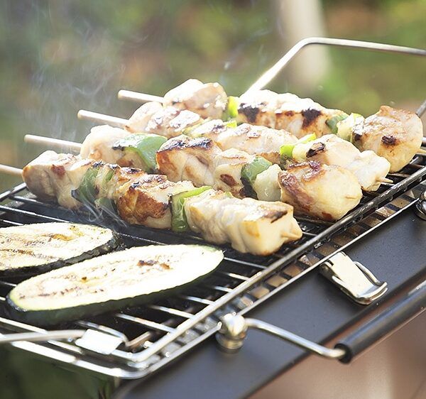 bærbar grill i bruk med 3 grillspyd på grillen