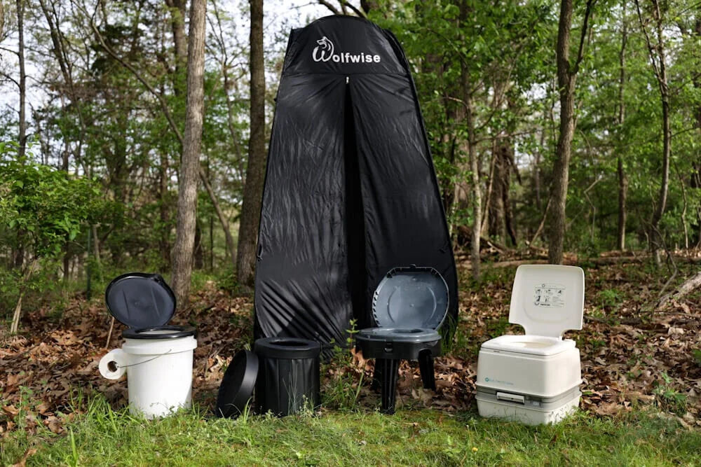 ulike campingtoaletter og utstyr plassert ved et toalett telt ute i naturen
