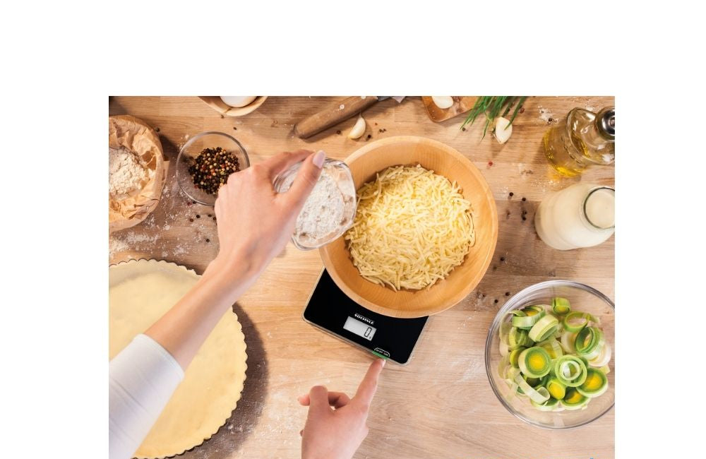 sort kjøkkenvekt i bruk med en bolle pasta under veiing
