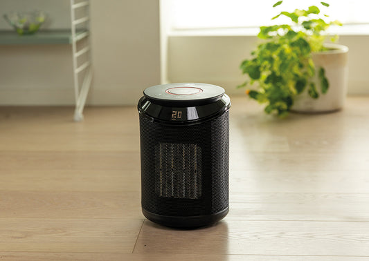 Svart varmevifte fra Beha, på tregulv ved en blomst i potte