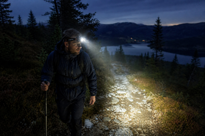 Aurora 2000 lumen hodelykt i bruk av an mann en mørk kveld på en sti med en sjø i bakgrunnen