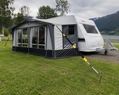 Tentsafe stormsikring montert på markise og fortelt ved campingvogn. Stormbånd med plugger og fjær gir ekstra sikring av markise i vind og ustabile værforhold på campingplassen.