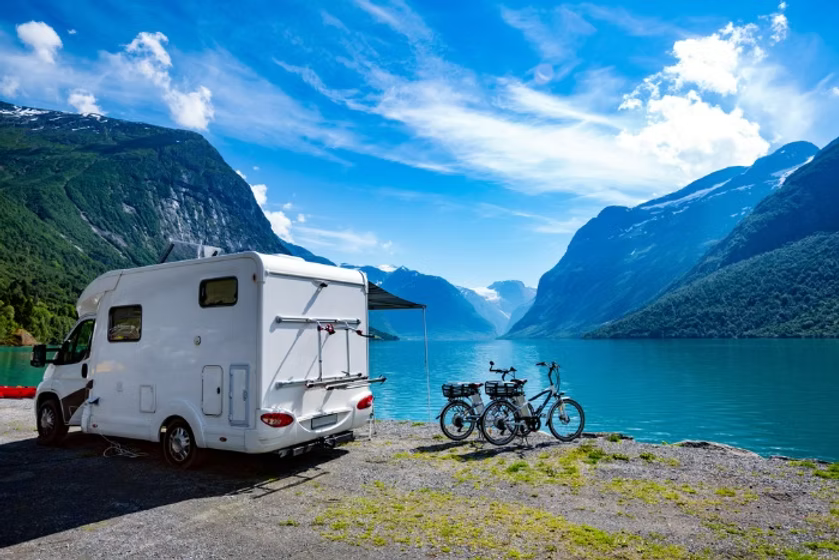 delintergret bobil parkert ved en fjord, med 2 el sykler utenfor